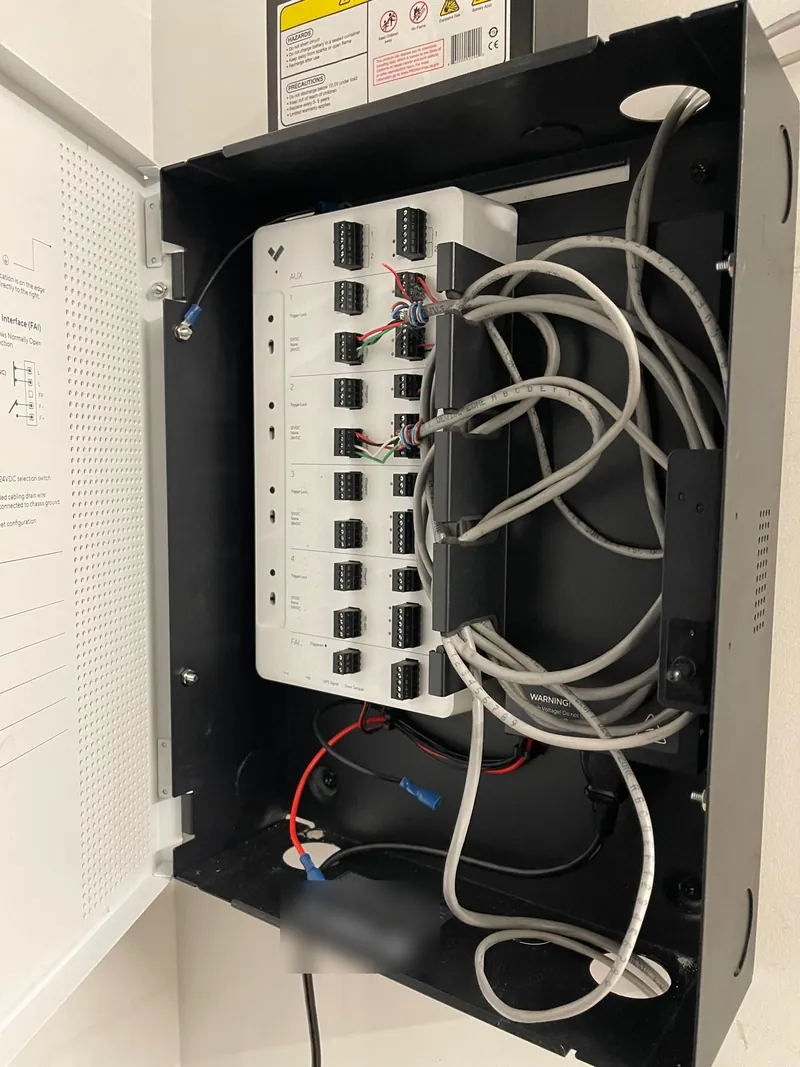 Open access control panel with door input terminals and gray network cables routed through cable management