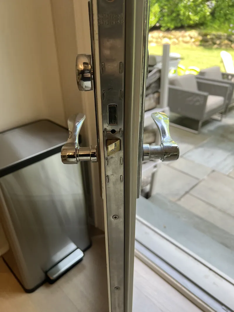 Multipoint lock faceplate with part numbers on a backyard patio door