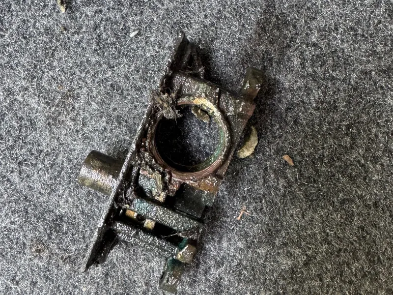 Heavily corroded bottom rail lock removed from a storefront door, lying on a carpet