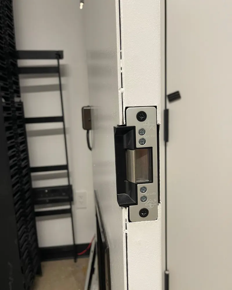 Electric strike installed in a white steel door frame, with its keeper visible