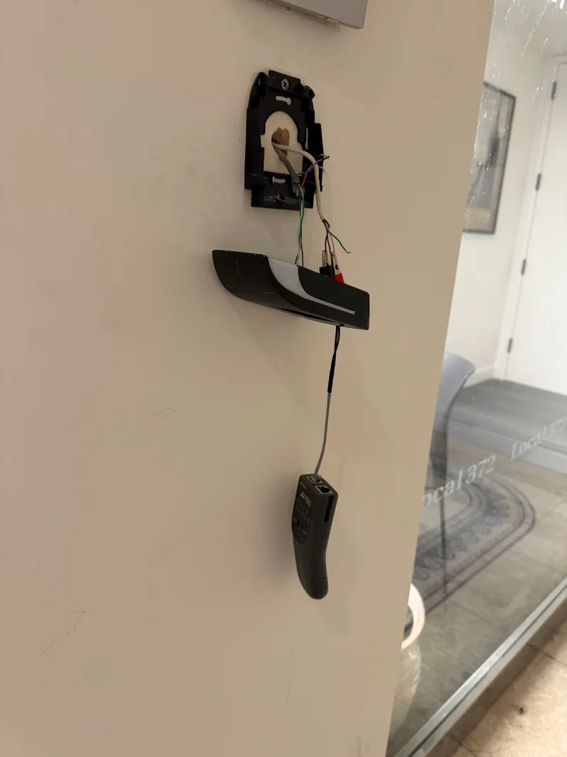 Low-voltage wires hanging from an opened device box on the frame of an office entrance door