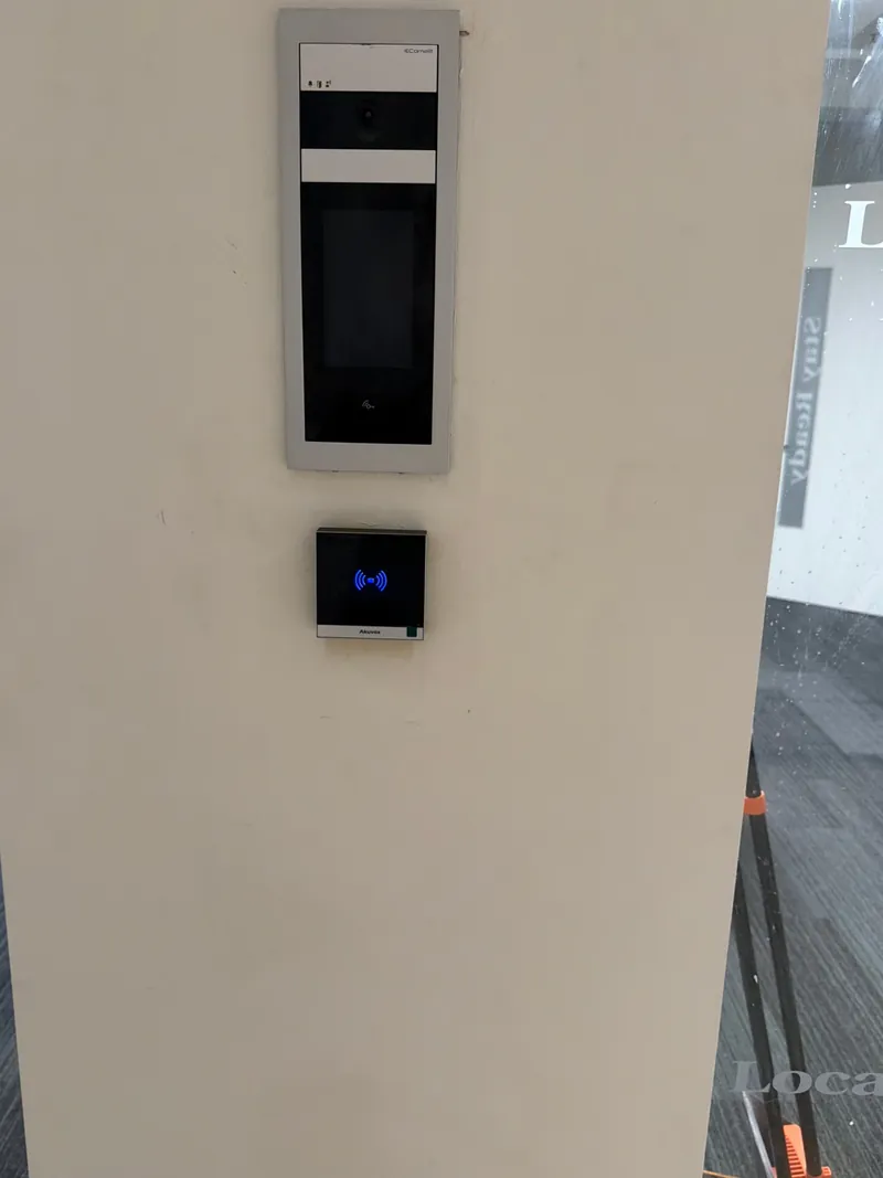 Video intercom panel and card reader mounted on a wall beside an entrance