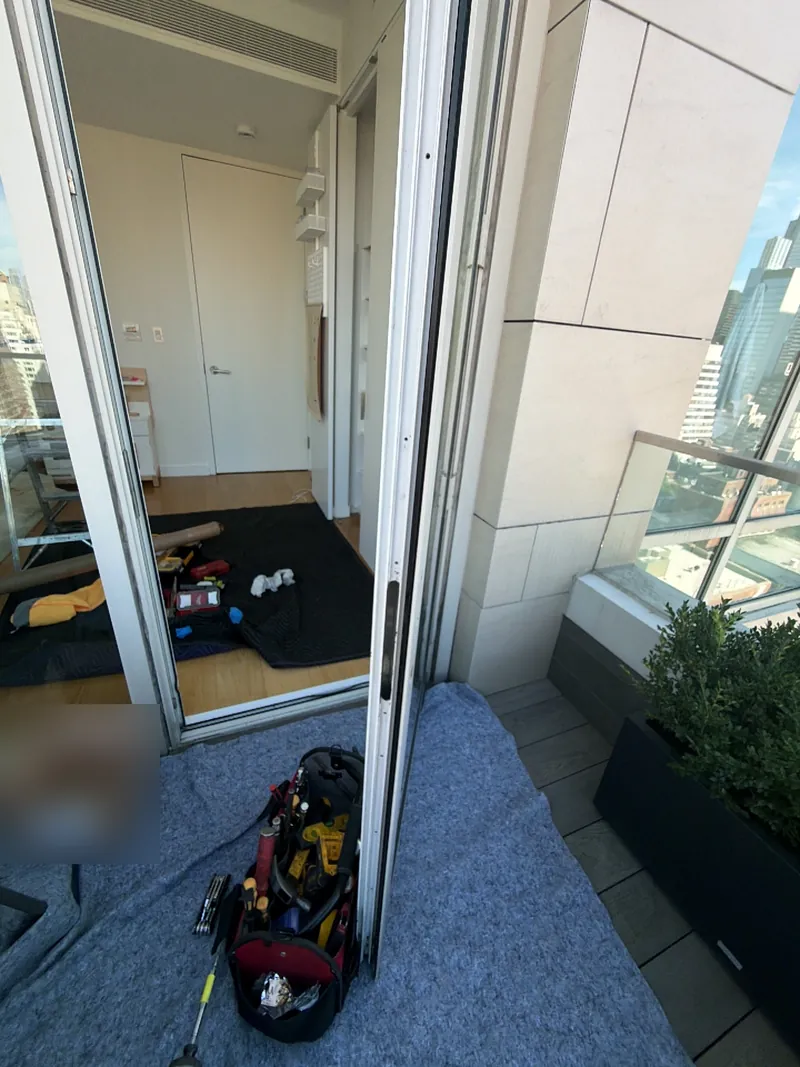 Technician's tools beside an open high-rise balcony door during lock repair