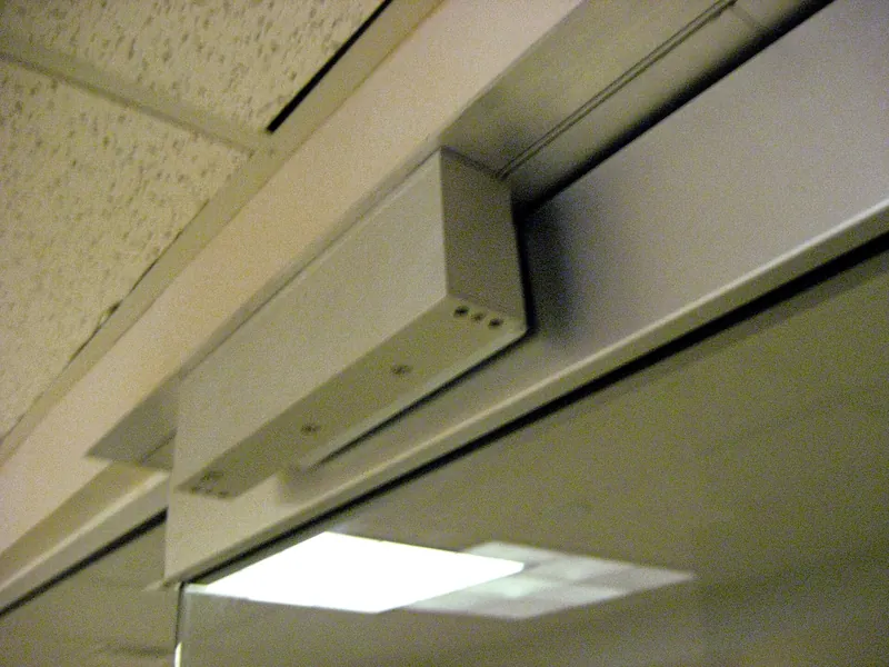 Electromagnetic door lock mounted under a door frame header