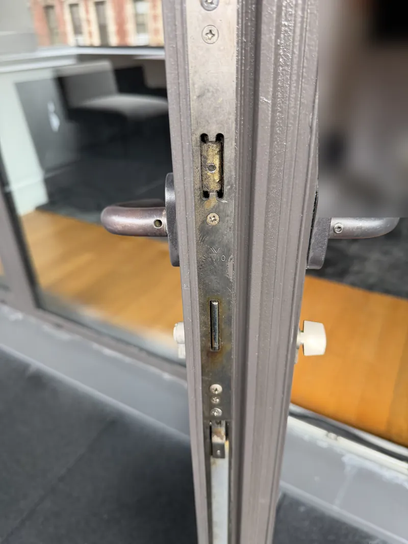 Savio multipoint lock faceplate on an aluminum balcony door edge