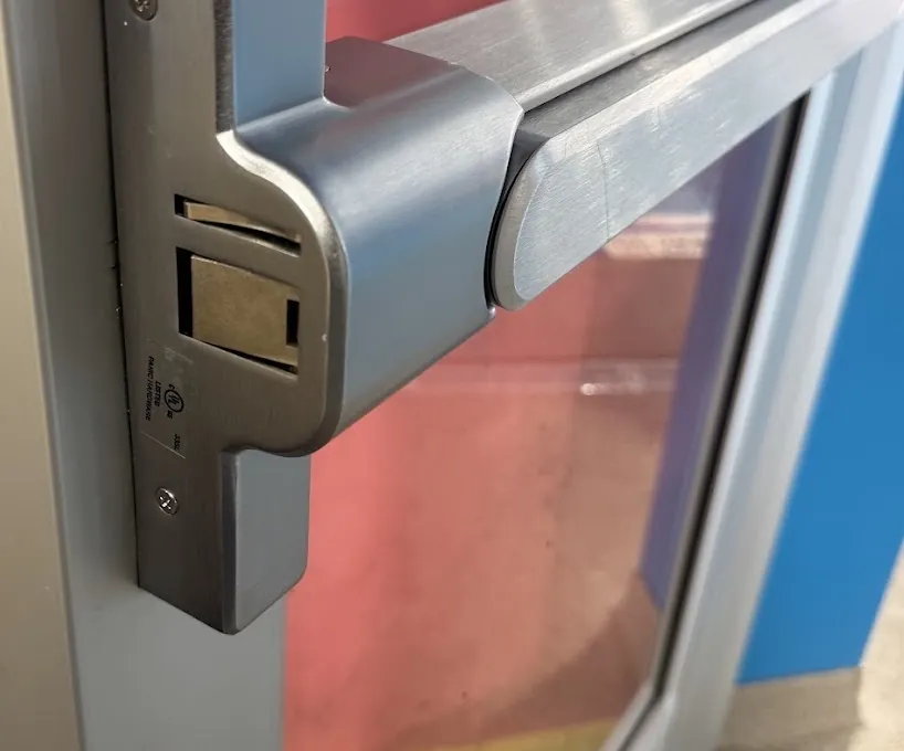 Compact exit-device latch housing and push pad on an aluminum storefront door