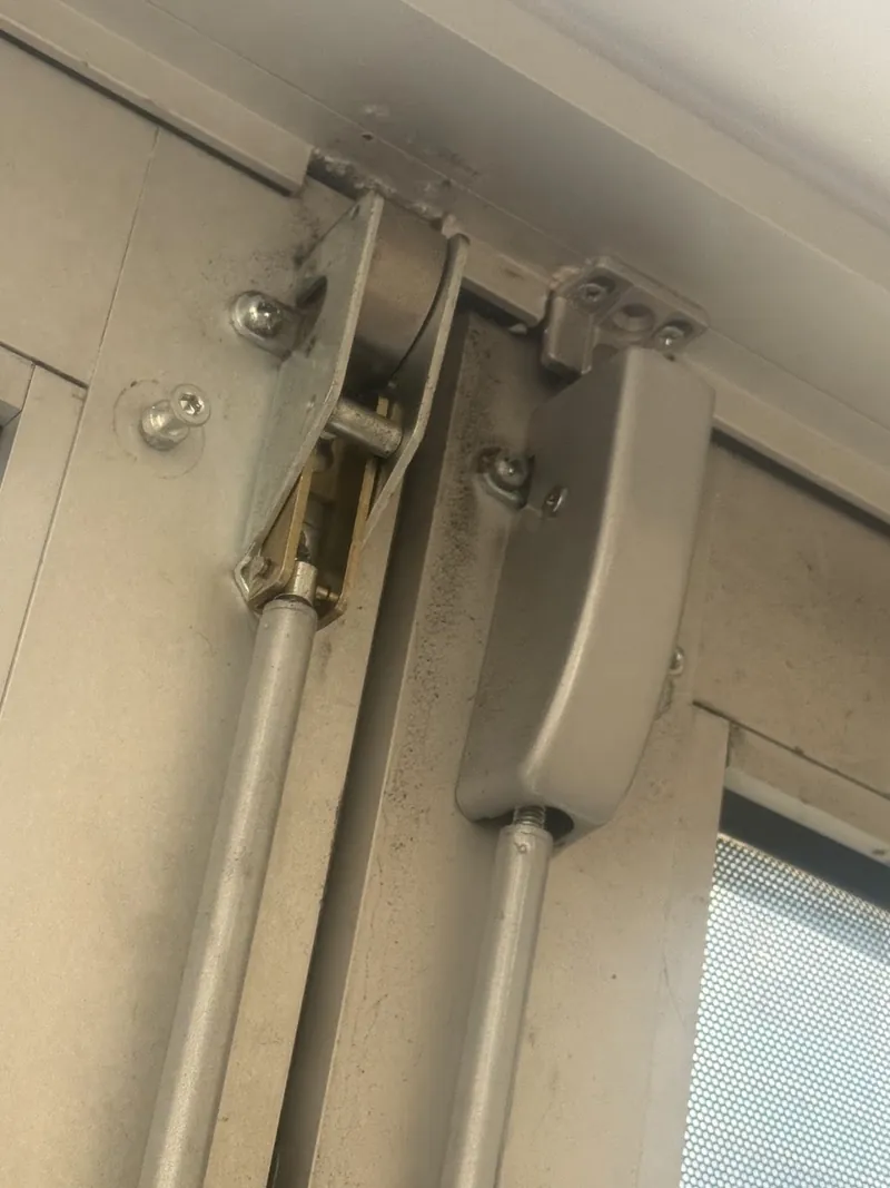 Upper surface vertical rods and top latches on a pair of metal doors, with one latch cover removed