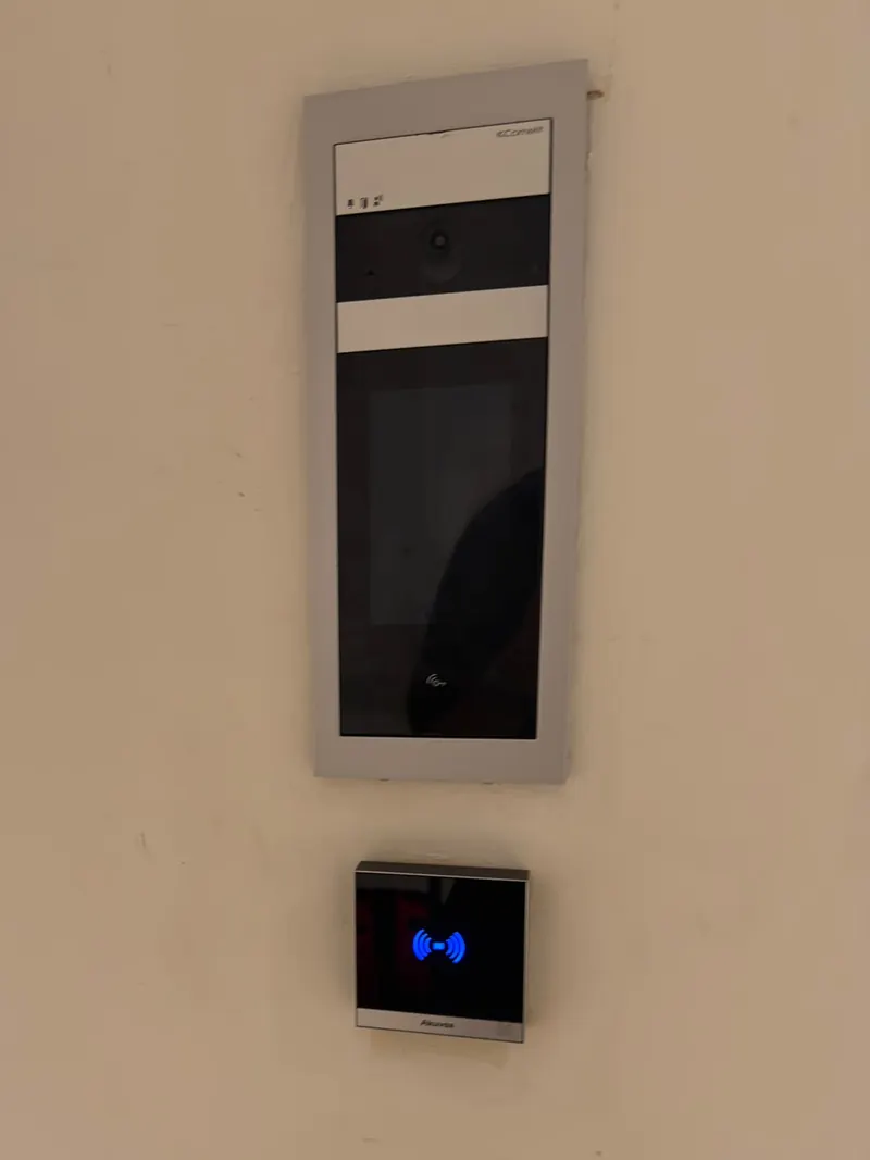 Video intercom station and a proximity fob reader mounted on a wall beside an entrance